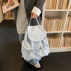 Detail of light blue drawstring backpack featuring small star patterns and flap closure