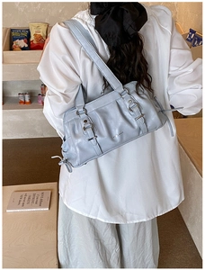 Light blue ruched leather Boston bag shown on a shoulder in a modern indoor cafe setting