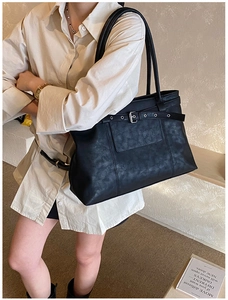 Detail of black pebbled leather tote bag with silver buckle and decorative belt strap