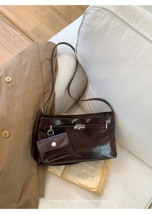 Detail der dunkelbraunen glänzenden Ledertasche mit Silberverschluss und Beutel