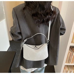 Minimalist light gray leather bucket bag with silver metal lock on model in office setting