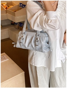 Close-up of light blue pleated handbag with silver buckle and metallic brand logo