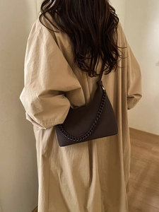 Detail of dark brown leather handbag with lychee texture and metallic chain decoration