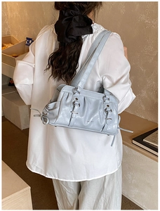 Detail of light grey pleated boston bag with decorative buckles and fringe tassels