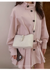 Detail view of cream white retro leather shoulder bag with silver buckle on a model