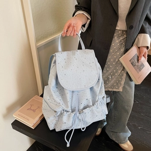Detail of light blue backpack with silver stars, drawstring closure and metal zippers