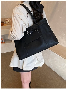 Detailed side view of black matte leather tote bag with silver buckle on female model