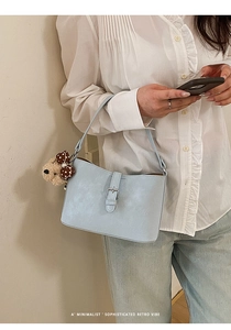 Detail of light blue leather shoulder bag with decorative buckle and cute bear charm