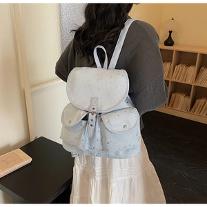 Close-up of light blue star print backpack with drawstring and dual front flap pockets