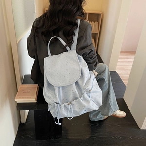 Detail of light blue backpack with silver star pattern and drawstring side pockets