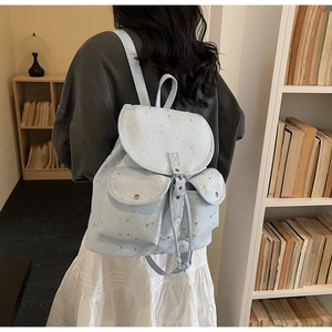 Detail of light blue star pattern backpack shown from side-view on person in a library