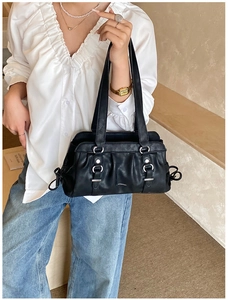 Detail of black textured leather bag with silver rings and white logo lettering