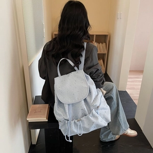 Lifestyle view of light blue star print backpack with drawstring and flap closure