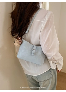 Detail of light blue faux leather bag with silver buckle and cute bear charm pendant
