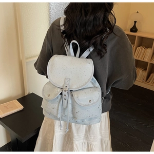 Detail of light blue star backpack with drawstring closure and silver metallic buckles
