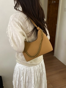 Detailed back view of a minimalist camel leather half-moon shoulder bag with a gold chain