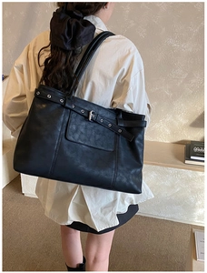 Detail of black PU leather tote bag showing vintage strap buckle and metal eyelets