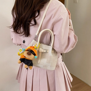 Detailed close-up of a beige mini bucket bag with a cute plush dog pendant charm