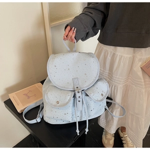 Detail of light blue canvas star backpack featuring buckle flap and metal star prints