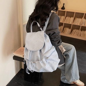 Detail showing stars pattern on light blue drawstring backpack worn by a model