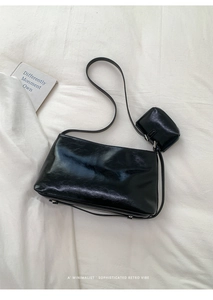 Details einer glänzenden schwarzen Schultertasche mit passender kleiner Tasche