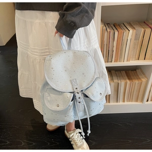 Detail of light blue star print canvas backpack with drawstring closure and silver stars
