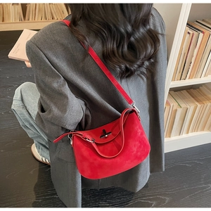 Detail shot of the red suede hobo bag with a silver metal clasp and thin strap