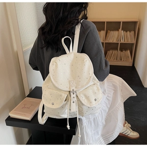 Detailed back view of a white canvas backpack featuring silver star patterns and drawstrings