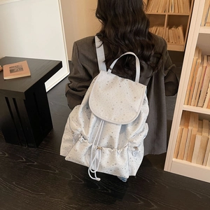 Detail of light blue canvas backpack with silver star patterns and drawstring closure