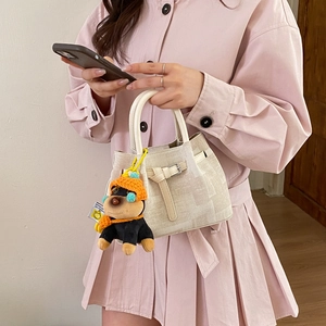 Detail of cream canvas handbag with round handles and a cute black puppy bag charm accessory