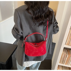 Detail of red suede bucket bag with black metal twist lock on model in office setting