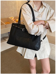 Detail shot of black leather tote bag with silver buckle and vintage strap design