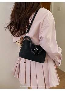 Close-up of black suede shoulder bag with silver metal buckle and cute bear pendant