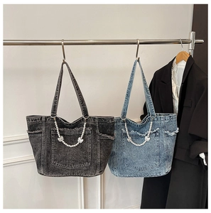 Detail of washed denim tote bag featuring pearl bow charms and distressed fringe pockets