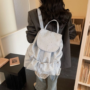 Close-up of light blue drawstring backpack featuring silver star prints and zipper pockets