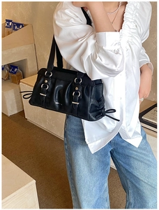 Detail of black leather underarm bag with ruffle texture and adjustable silver buckle