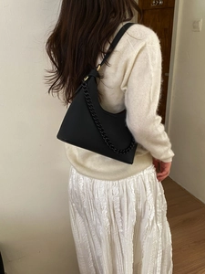 Detail shot of a black hobo shoulder bag with textured leather and decorative chain strap