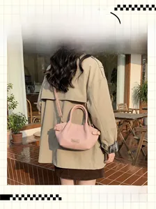 Nahaufnahme der rosa Handtasche mit Litschimaserung, Rundgriff und metallischem Logo