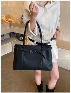 Detail view of black matte leather tote bag with stylish buckle strap and shoulder strap