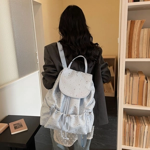 Detail view of light blue star pattern backpack with drawstring closure on a model