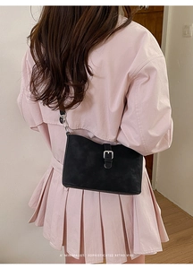 Detail of minimalist black retro crossbody bag with silver metallic buckle on a model