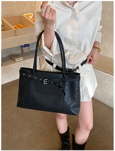 Detail of black matte leather tote bag featuring silver metal buckle and long straps