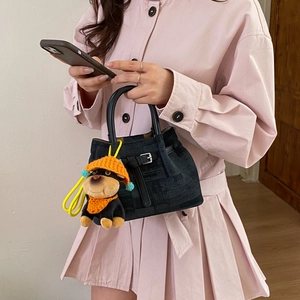 Close-up of navy textured bucket bag with cute dog charm and black buckle strap details