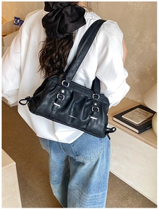 Detailed view of black pleated Boston bag with silver buckle and soft leather texture