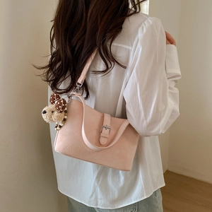 Pink matte leather shoulder bag with decorative buckle and plush bear charm on strap