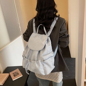 Detail view of light blue star-patterned backpack with drawstring and flap closure