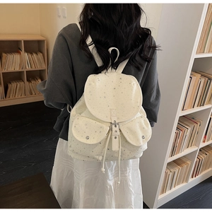 Detail view of cream star-patterned backpack showing side pockets and flap closure