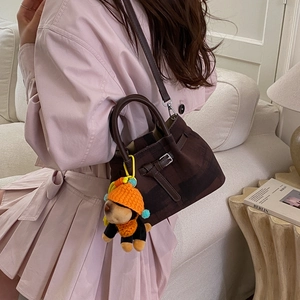Detail of dark plaid canvas bucket bag with leather strap and cute puppy charm on a sofa