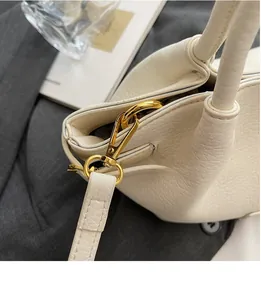 Detailansicht goldener Metallhaken und beige Leder mit Litschi-Maserung auf der Tasche
