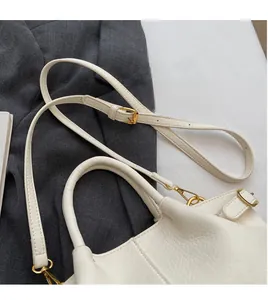 Detail der cremeweißen Lederhandtasche mit goldener Hardware und verstellbarem Gurt